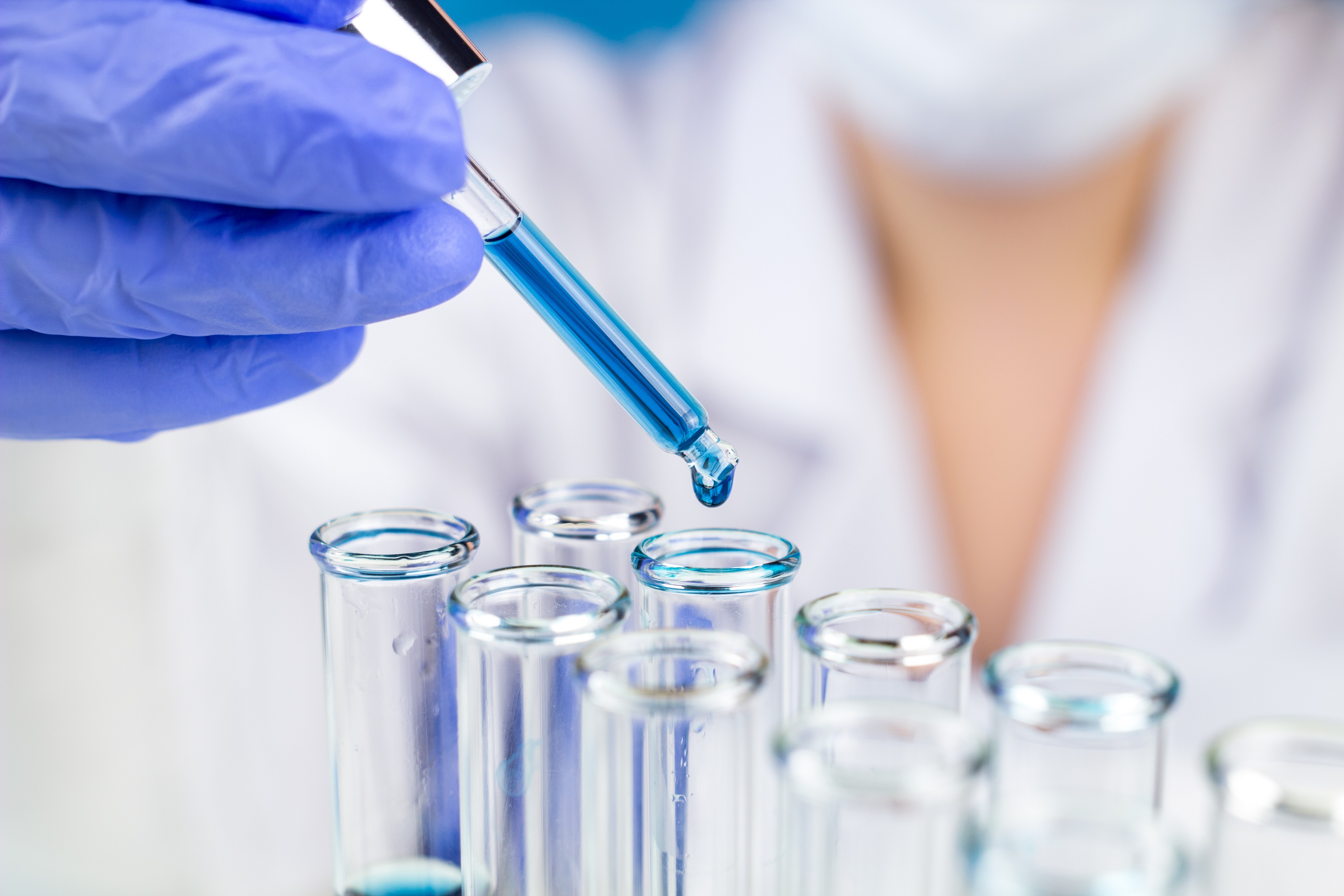 Sientist With Pipette Blue Water Drop In Test Tubes In Laboratory.
